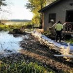 Flooding right next to a house with long line of sandbags piled up to keep the water out.