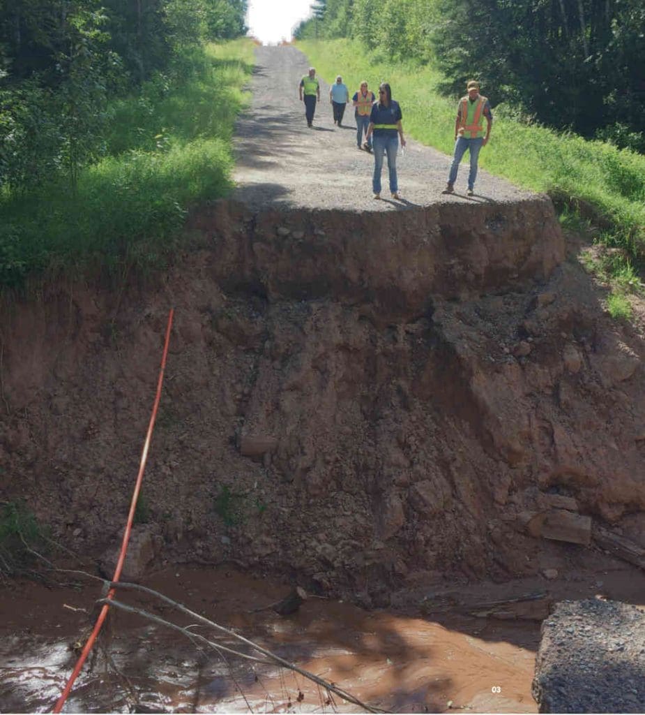 Safety crews looking down at a washed out road