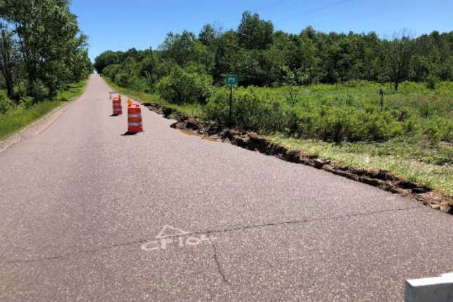 A photo down a road with a sinkhole off to the side
