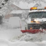 A plow truck pushing snow off the road
