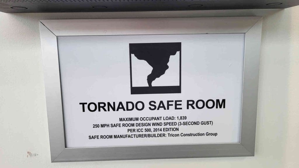 A sign for a Tornado Safe Room with info about the room like limit and how much wind it can handle