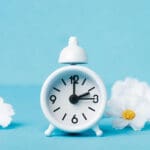 An alarm clock surrounded by spring flowers