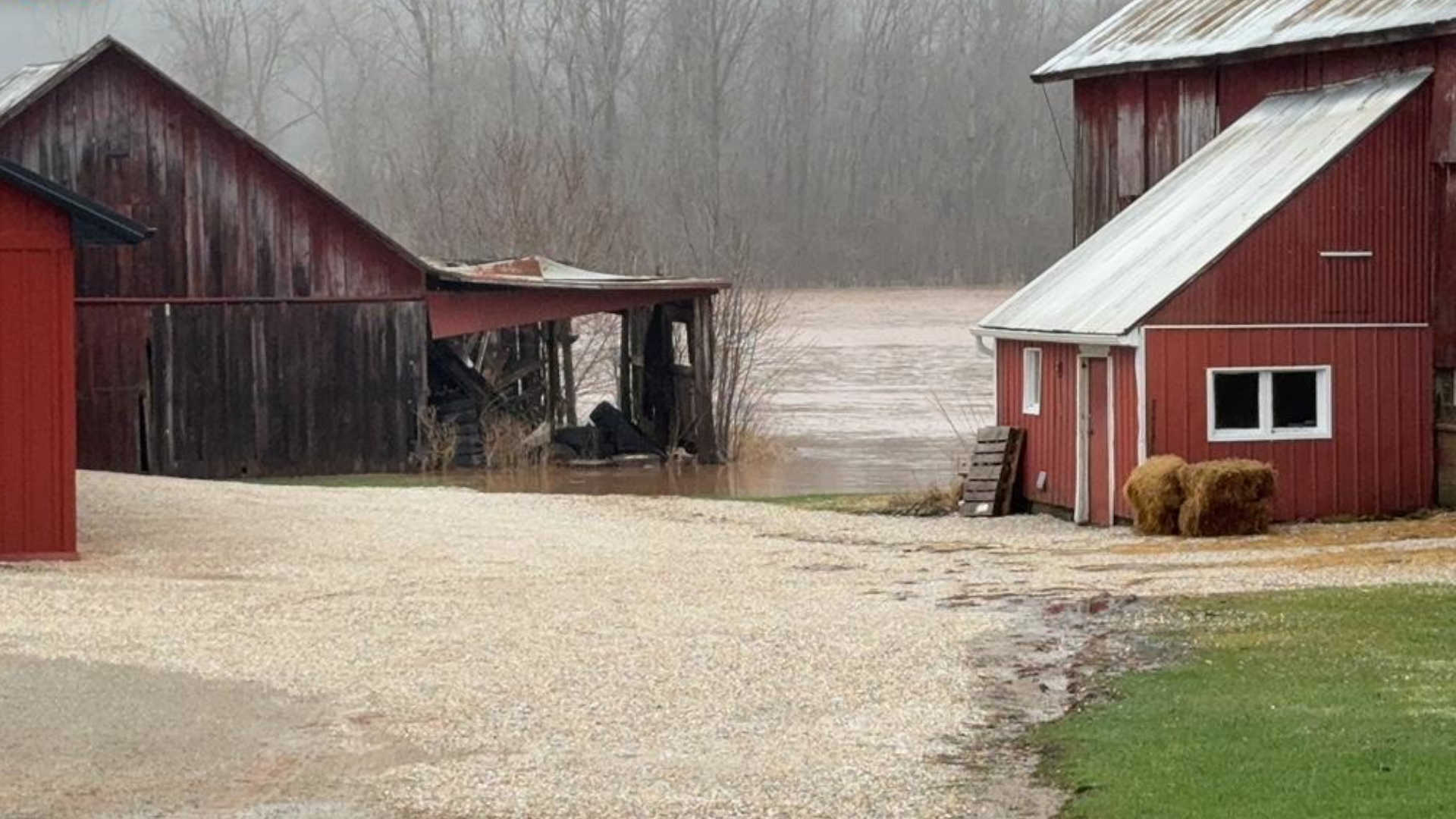 Barns with approaching floodwaters up to and above the foundations.