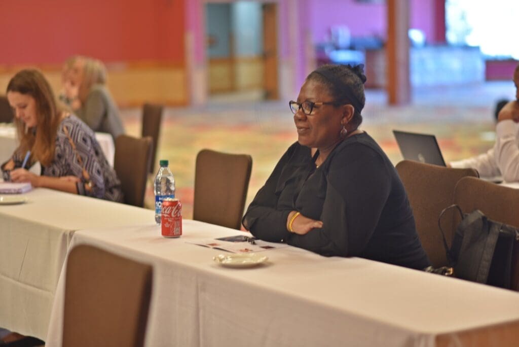 Woman sitting at table listening to conference panel