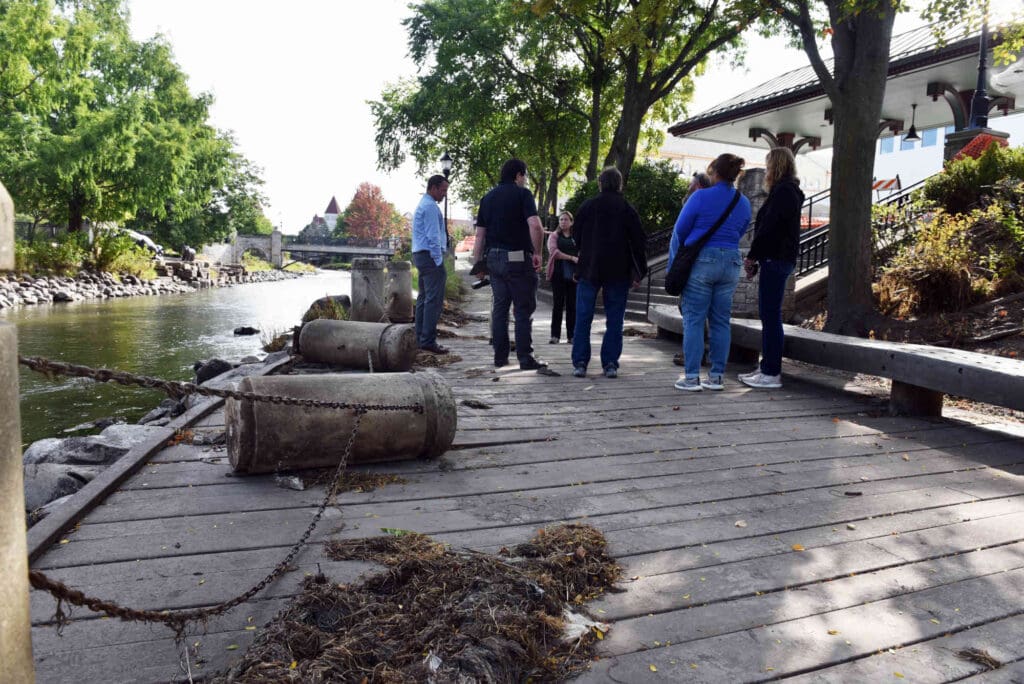 people on a walkway next to a river that is covered in debris after flooding